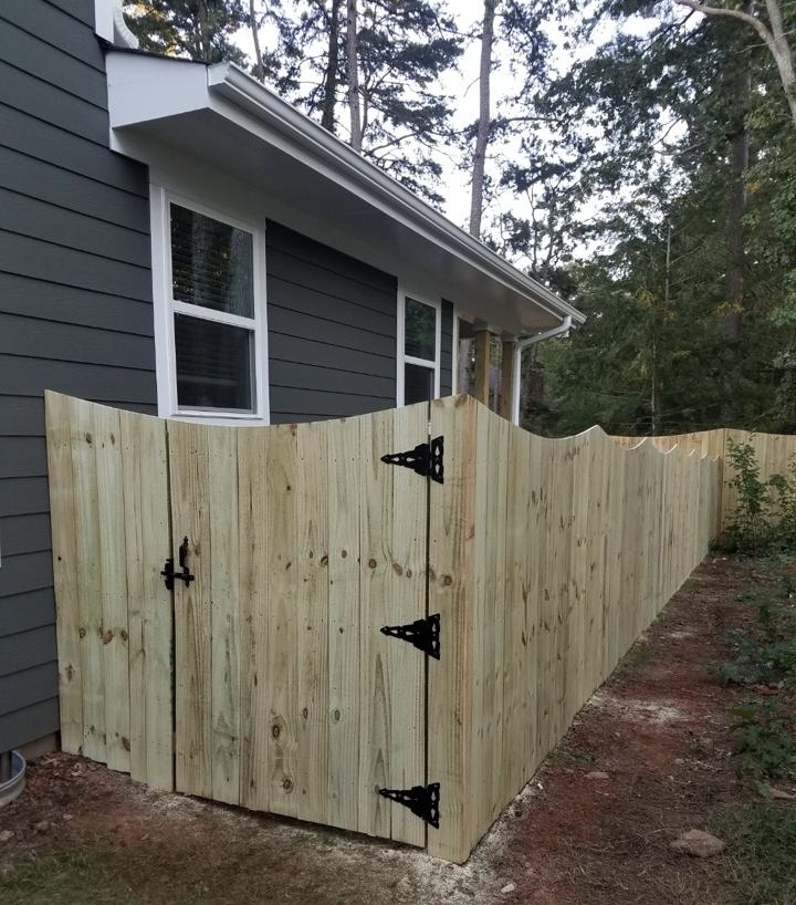 New wooden privacy fence with gate hardware installed beside a home