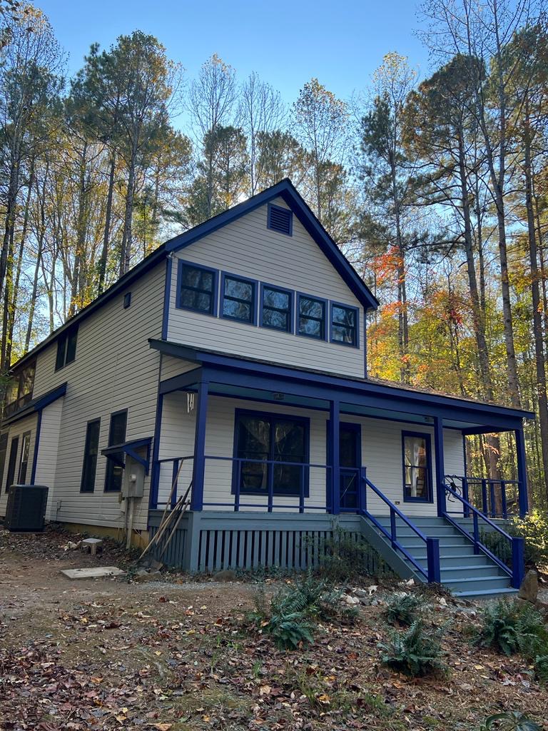 Two-story home with gray siding and green trim before exterior painting